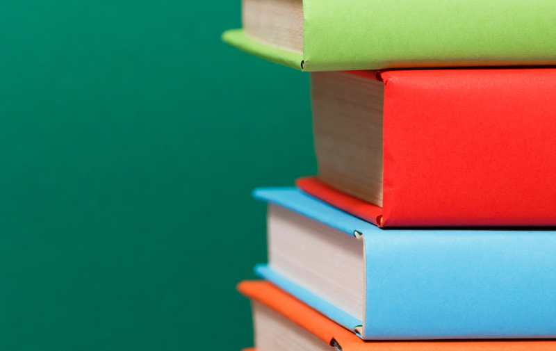 A stack of books sits on a green background.