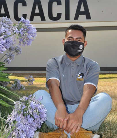 student with a mask sitting on the ground