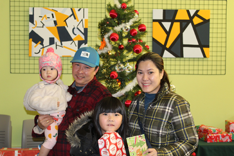 Parents with their children sitting next to a decorated Christmas tree