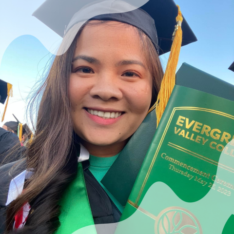 A student is smiling and holding a graduation broshure