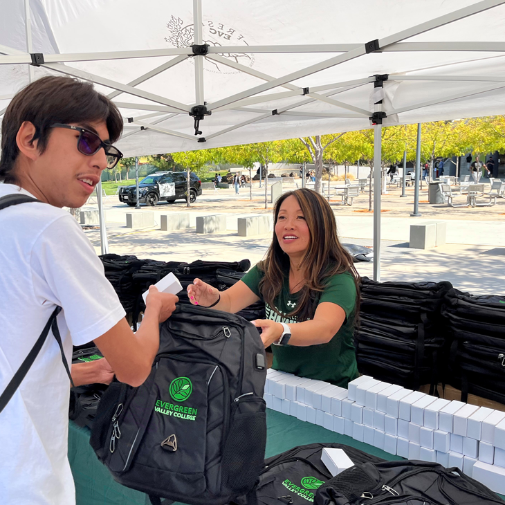 President Gilkerson hands out a free backpack to a student at the start of the Fall semester